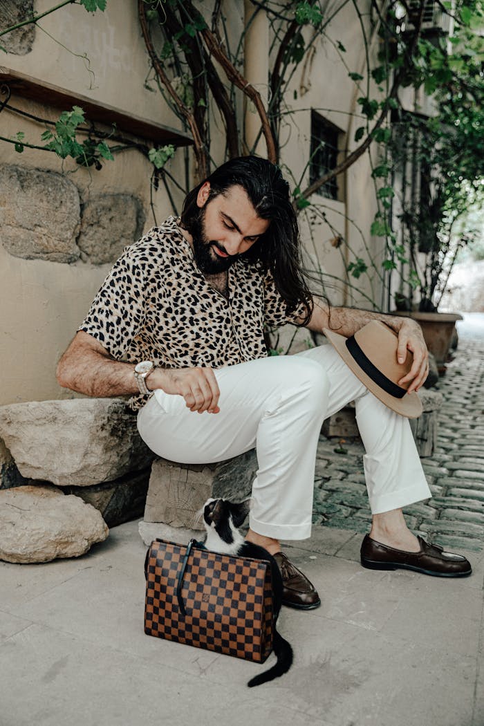 about-img Fashionable man in leopard print interacts with a cat on a Baku sidewalk, exuding elegance and style.
